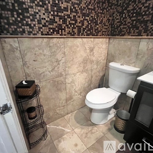 A bathroom with a toilet, a towel rack, and a tiled wall.
