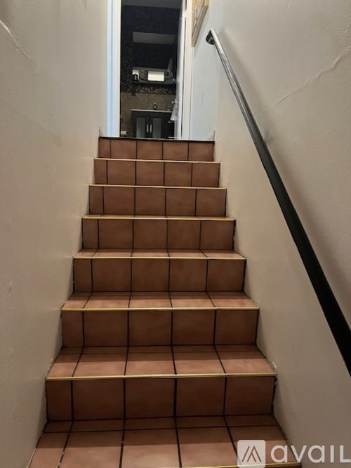 A set of stairs with a black handrail.