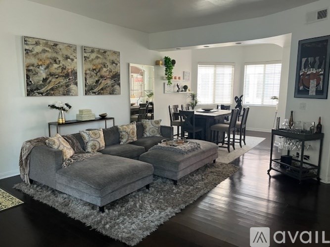 A living room with a grey couch and a grey ottoman with a rug in front of it.