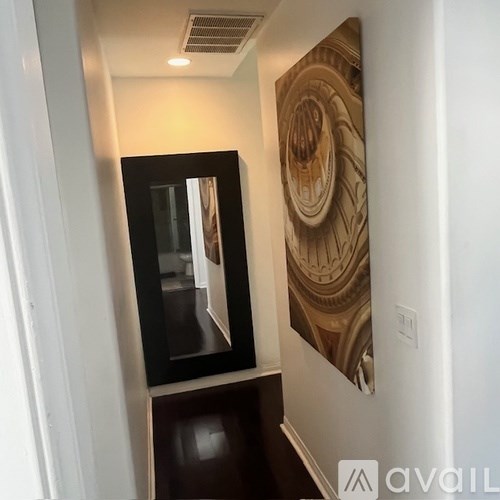 A hallway with a framed mirror and a picture on the wall.