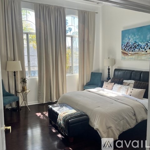 A bedroom with a large bed and a painting on the wall.