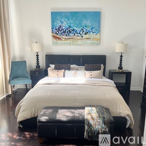 A bedroom with a large bed and a painting on the wall.