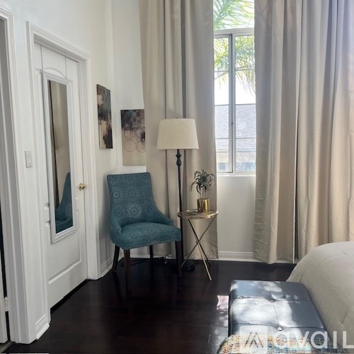 A blue chair sits in a room with a white couch and a lamp.