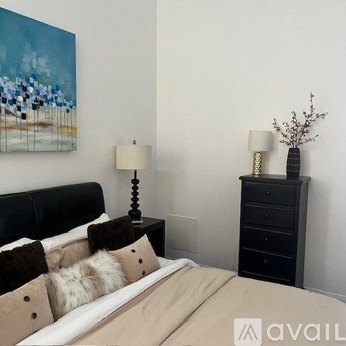 A bedroom with a bed, nightstand, and a painting on the wall.