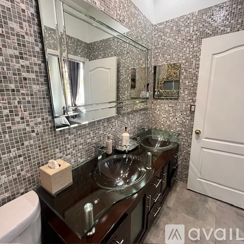 A bathroom with a mirror, sink, and tiled walls.
