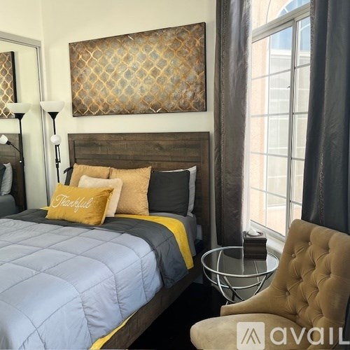 A bedroom with a bed, a chair, and a painting on the wall.