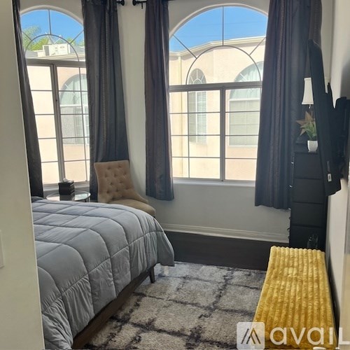 A bedroom with a large bed and a window with curtains.