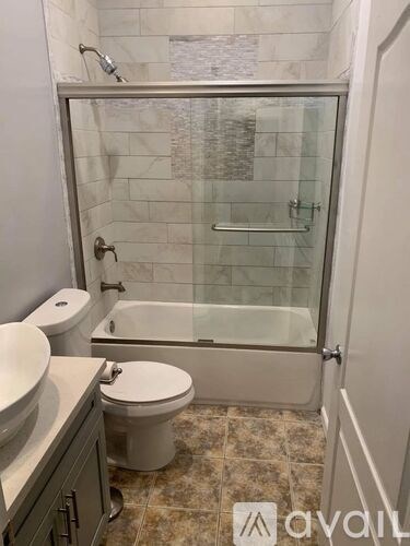A bathroom with a glass shower door and a white toilet.