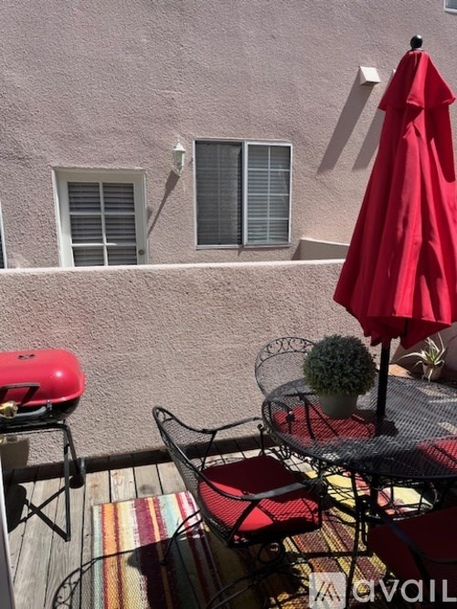 A red umbrella is on a table outside a building.