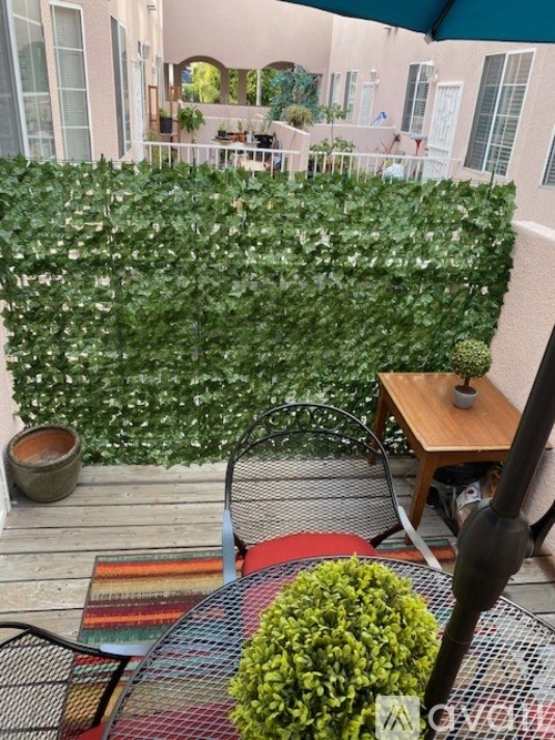 A green hedge covers a wall in a patio area.