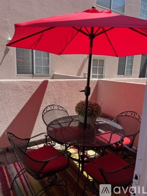A red umbrella is open over a table with chairs.