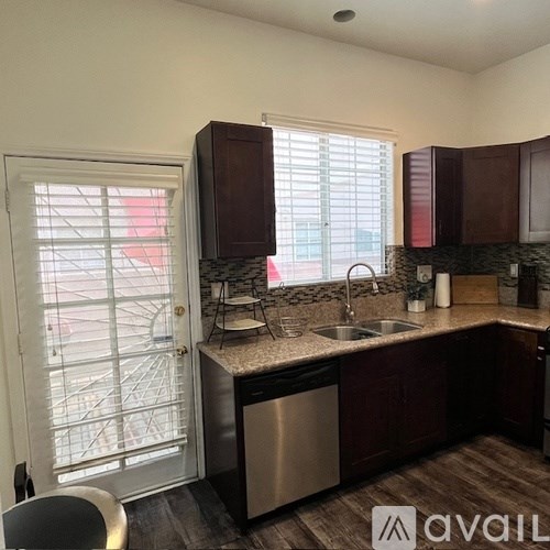 A kitchen with dark brown cabinets and a stainless steel dishwasher.