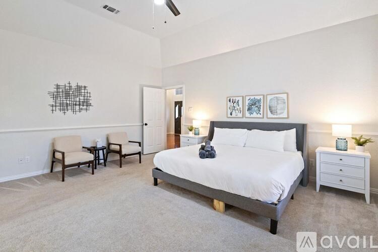 A bedroom with a bed, two chairs, and a table.