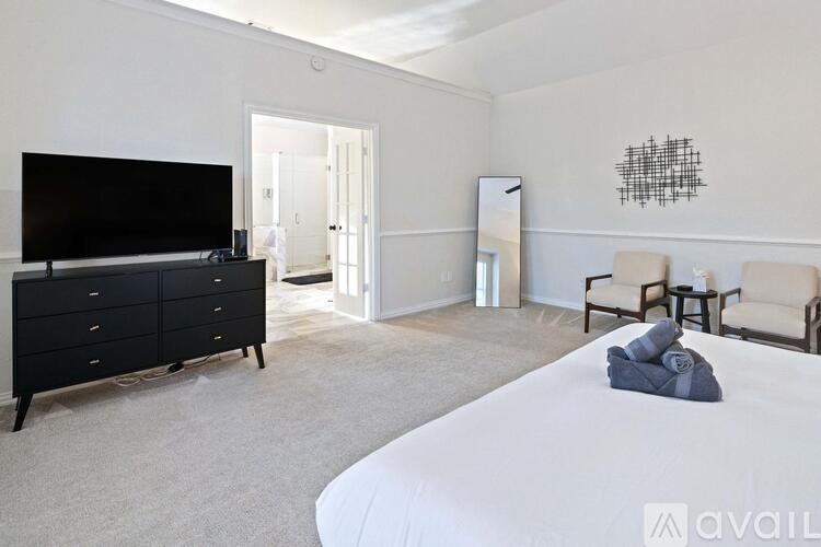 A bedroom with a large bed, a dresser, and a television.