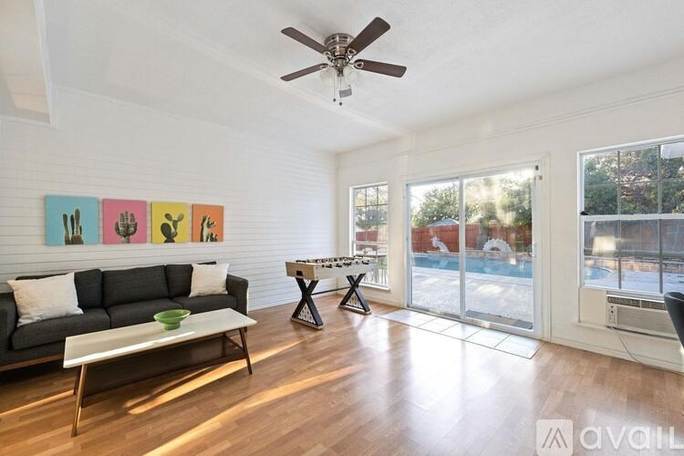 A living room with a couch, a coffee table, and a fan.