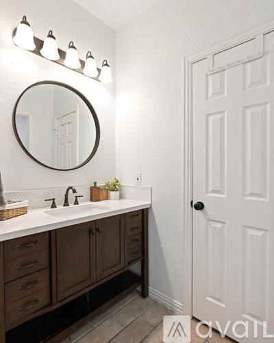 A bathroom with a white door and a round mirror above a sink.