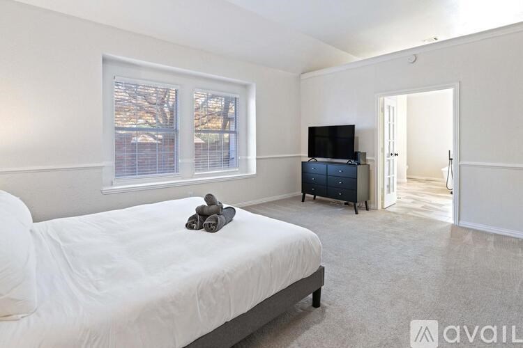 A bedroom with a bed, a TV, and a window with a view of trees.