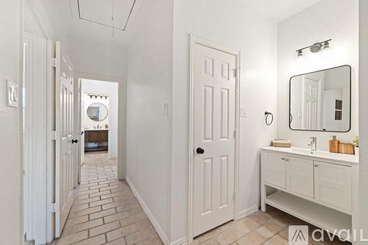 A bathroom with a white door, a mirror, and a vanity.