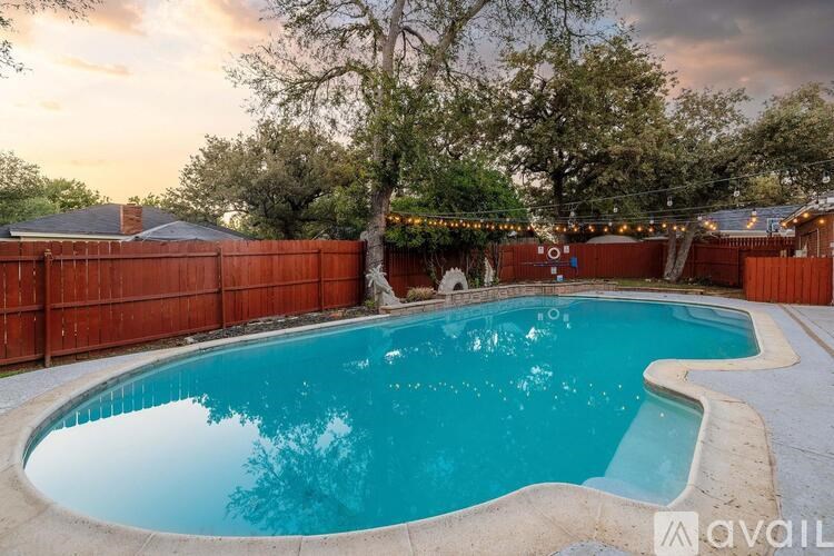 A swimming pool surrounded by a wooden fence and trees.