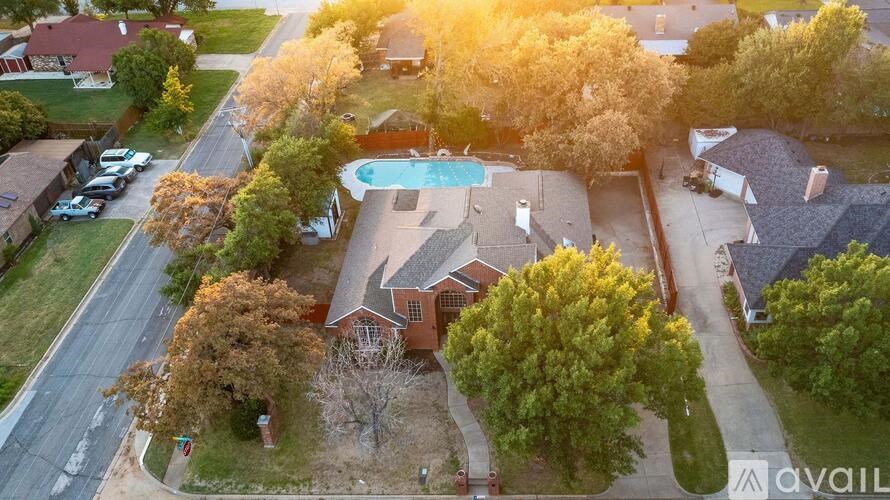 An aerial view of a residential area with houses, trees, and a swimming pool.