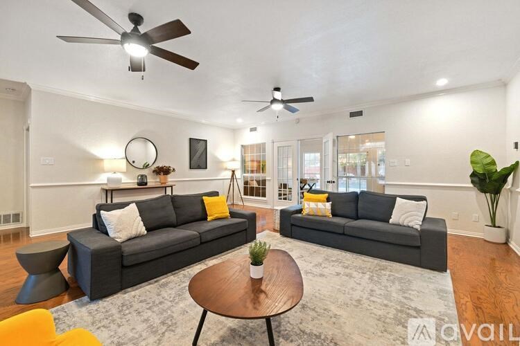 A living room with a grey couch, a coffee table, and a ceiling fan.