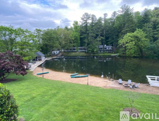 A lake surrounded by trees and a grassy area with chairs.