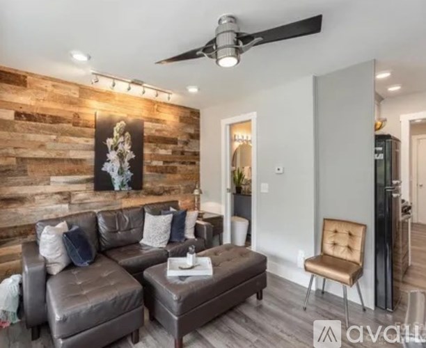 A living room with a brown leather couch and a wooden wall.