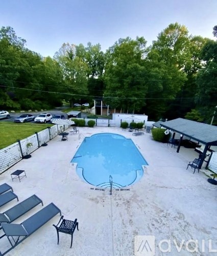 A pool surrounded by a fence and lounge chairs.