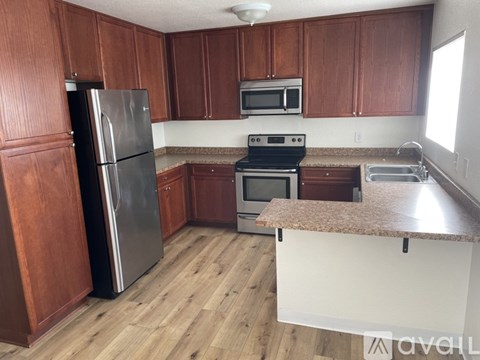 A kitchen with wooden cabinets and a black refrigerator.