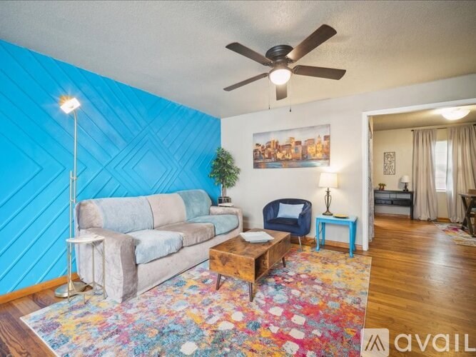 A living room with a blue accent wall and a ceiling fan.