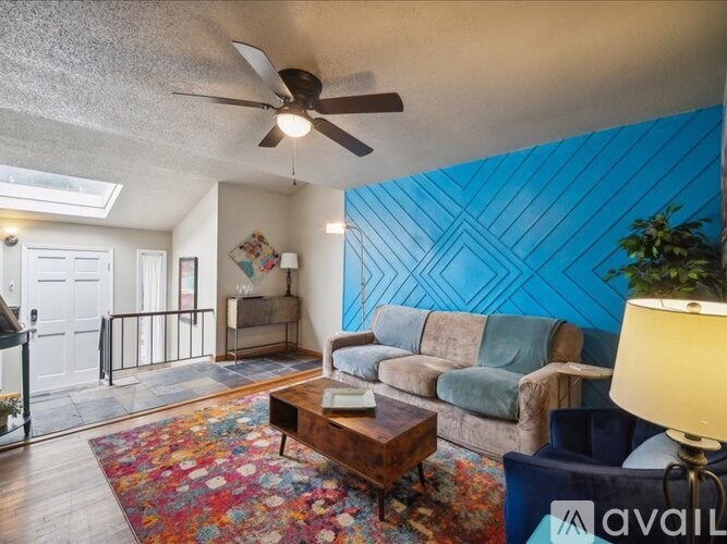 A living room with a blue wall and a ceiling fan.