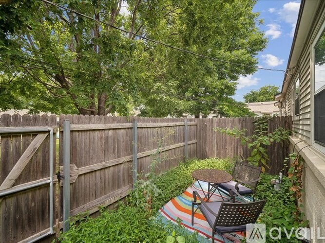 A backyard with a wooden fence and a chair with a colorful cushion.
