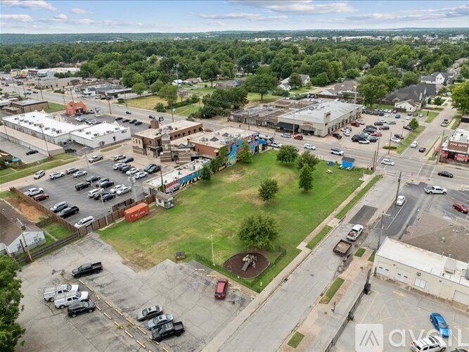 A large parking lot with several cars and a green field in the middle.