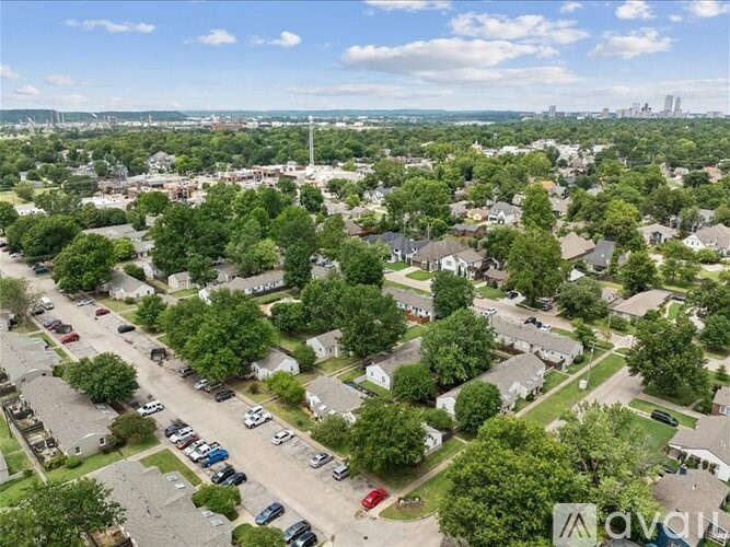 A suburban neighborhood with a parking lot in the foreground and a city skyline in the distance.