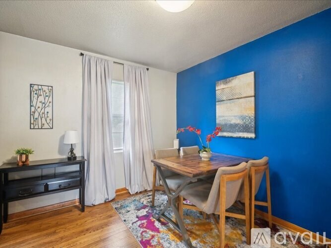 A room with a blue wall and a wooden table with chairs.