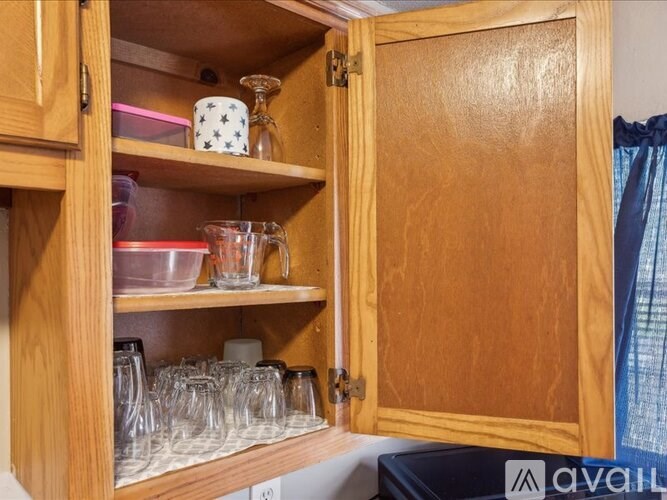 A wooden cabinet with glasses and cups on the shelves.