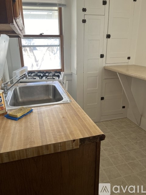 A kitchen with a wooden counter top and a stainless steel sink.