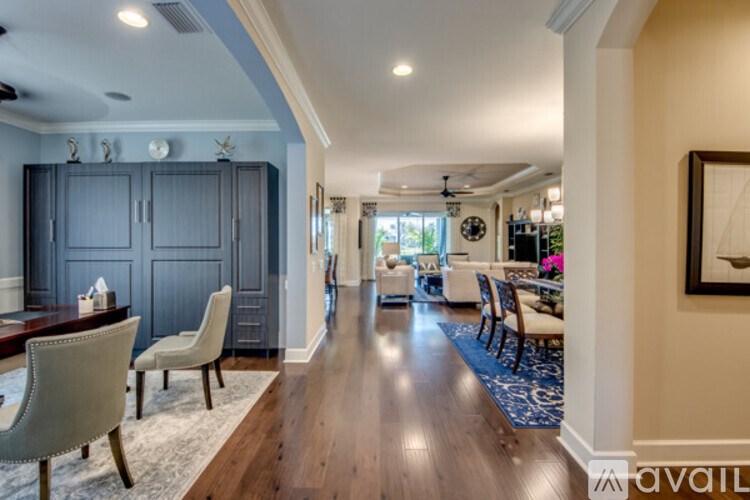 A spacious dining room with a wooden floor and a long table with chairs.