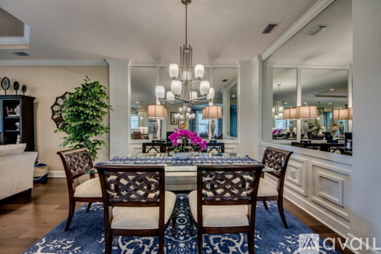 A dining room with a table set for four and a chandelier hanging from the ceiling.