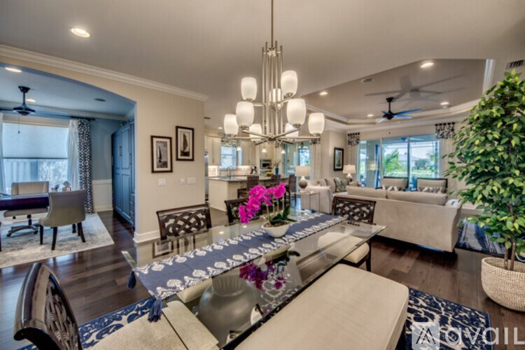 A modern living room with a glass table and a chandelier.