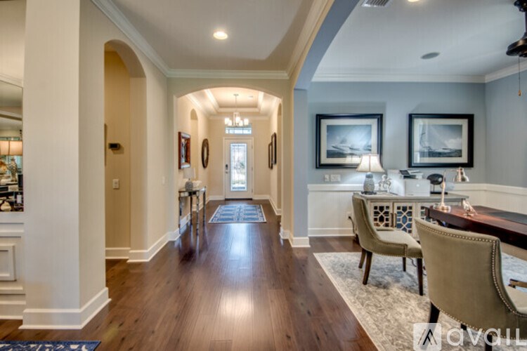 A hallway with a wooden floor and a chair with a white cushion.