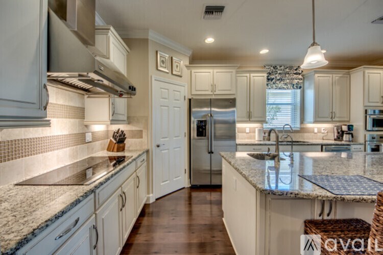A kitchen with white cabinets and a marble countertop.