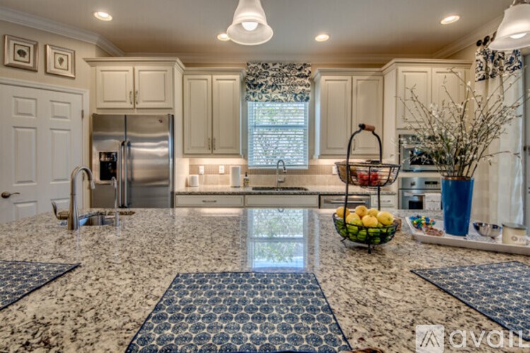 A kitchen with granite countertops and a bowl of fruit on the island.