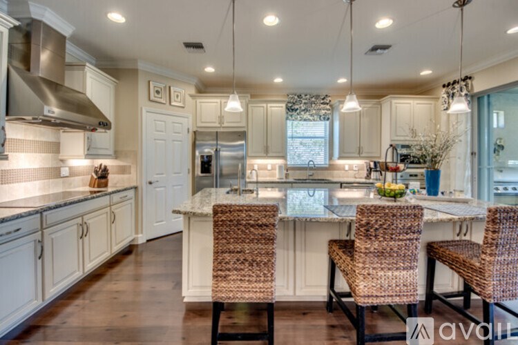 A kitchen with a center island and chairs.