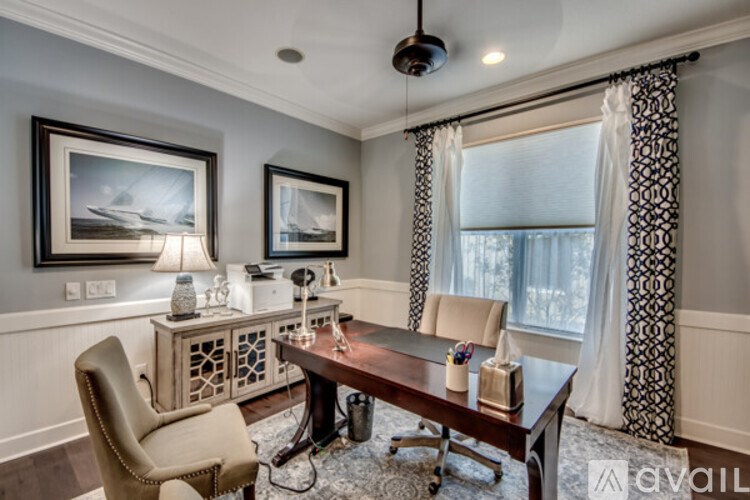 A room with a brown leather chair, a wooden table, and a painting on the wall.