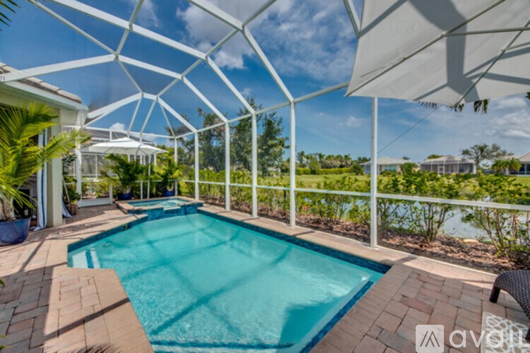 A pool surrounded by a white fence and a white umbrella.