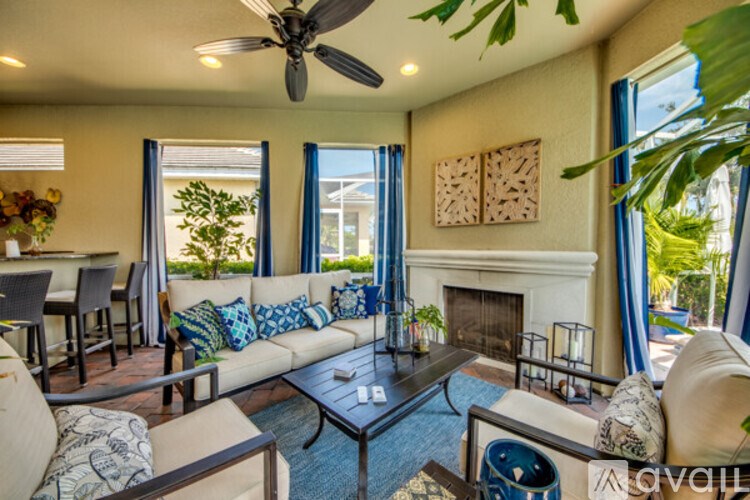 A living room with a fireplace, couches, and a ceiling fan.