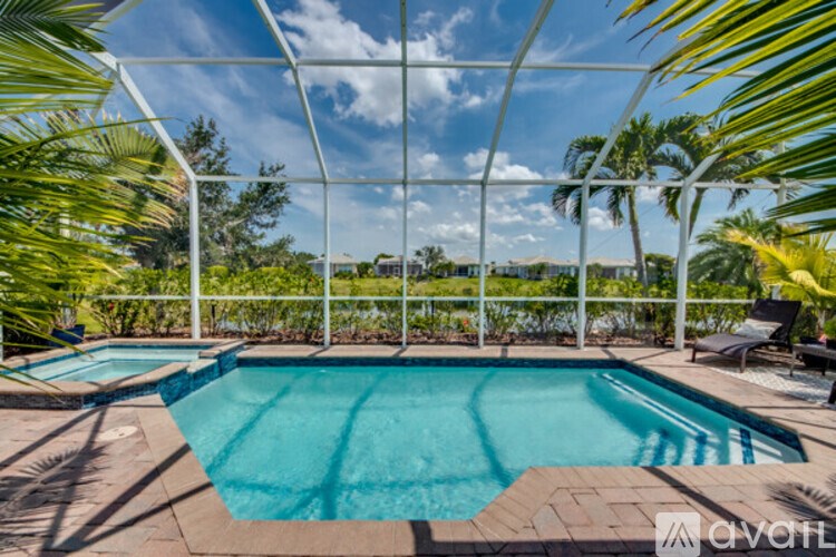 A pool surrounded by palm trees and a white fence.
