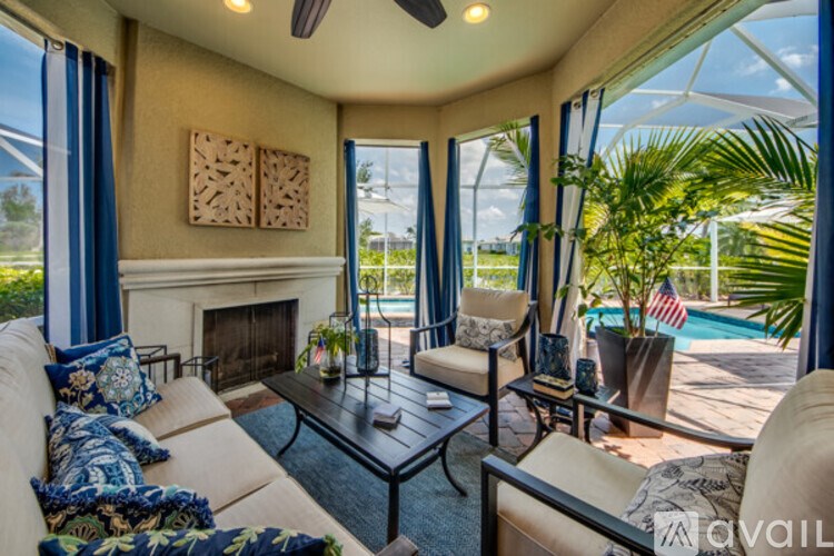 A living room with a fireplace and a pool outside the window.