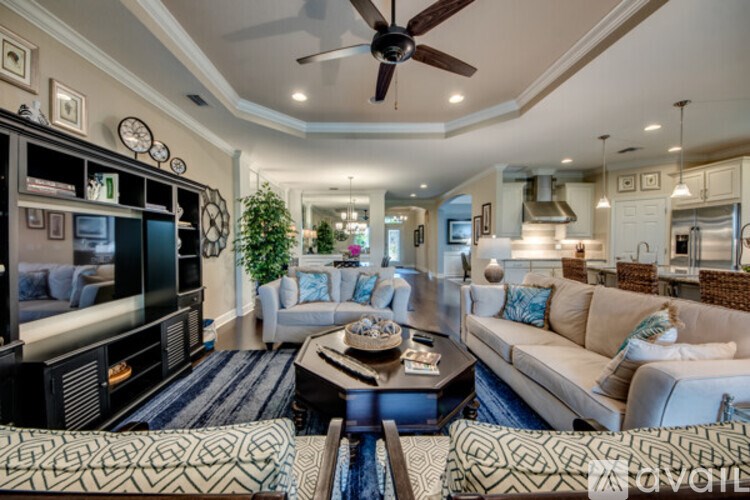 A living room with a television, couches, and a ceiling fan.